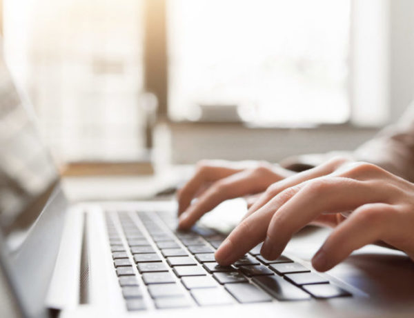 Typing on laptop closeup, chatting in Facebook